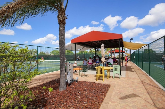 view of community featuring a tennis court and fence