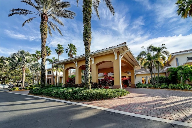 view of front of property featuring a tiled roof, decorative driveway, and stucco siding