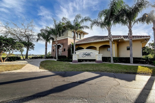 view of front of property with a garage, a tile roof, a front lawn, and stucco siding