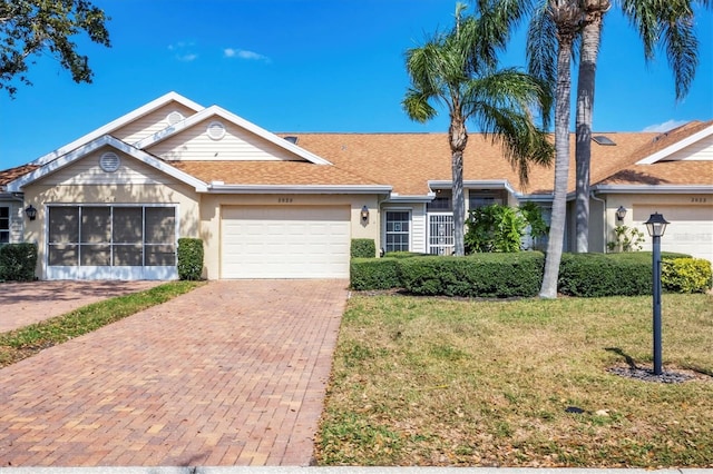 single story home with a garage, decorative driveway, a front lawn, and stucco siding