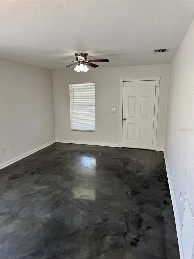 unfurnished room with a textured ceiling, concrete floors, visible vents, and baseboards