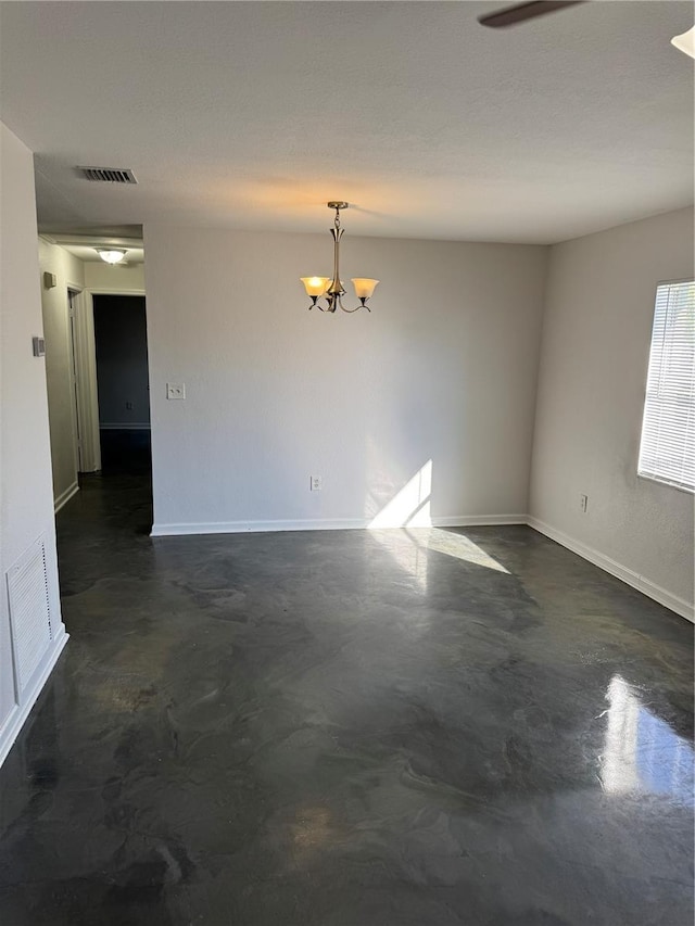 spare room with finished concrete floors, a chandelier, and visible vents