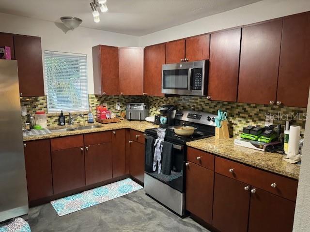 kitchen featuring light stone counters, appliances with stainless steel finishes, decorative backsplash, and a sink