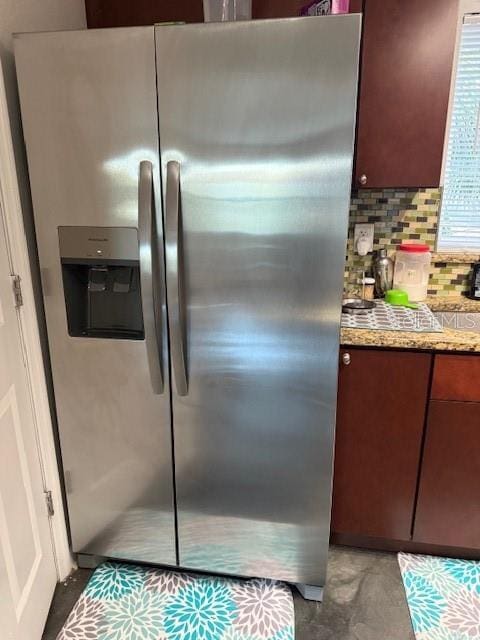 room details featuring light stone countertops, tasteful backsplash, and stainless steel fridge with ice dispenser