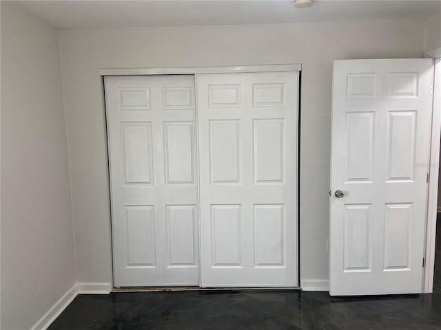 interior space with concrete flooring, a closet, and baseboards