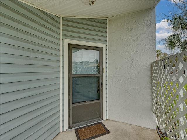 view of exterior entry featuring fence and stucco siding