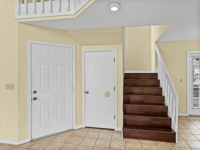 stairway featuring baseboards, a textured ceiling, and tile patterned floors