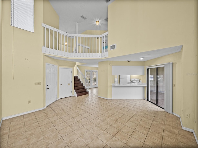 unfurnished living room featuring tile patterned flooring, visible vents, stairway, and baseboards