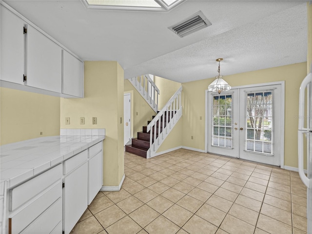 kitchen with tile countertops, white cabinetry, visible vents, and light tile patterned flooring