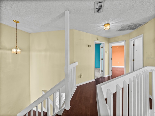 hall with baseboards, visible vents, an upstairs landing, and wood finished floors