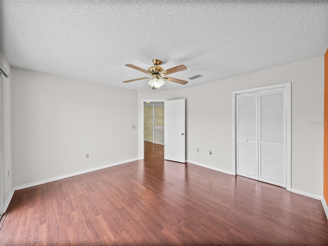 unfurnished bedroom featuring a textured ceiling, wood finished floors, a ceiling fan, visible vents, and baseboards