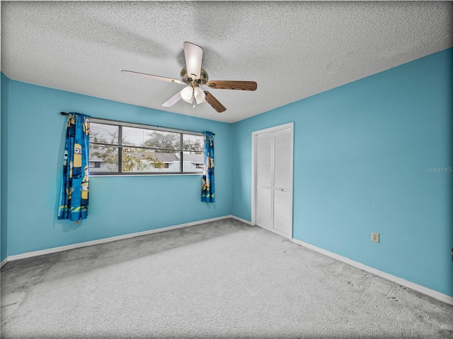 spare room featuring carpet flooring, ceiling fan, a textured ceiling, and baseboards