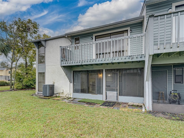 back of property featuring stucco siding, a lawn, and central AC unit