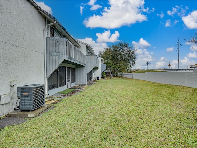 view of yard with central AC and a balcony