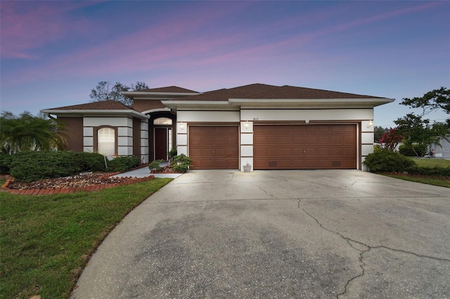 prairie-style house with driveway, an attached garage, and stucco siding