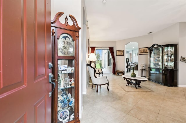 foyer entrance featuring light tile patterned floors, baseboards, and arched walkways