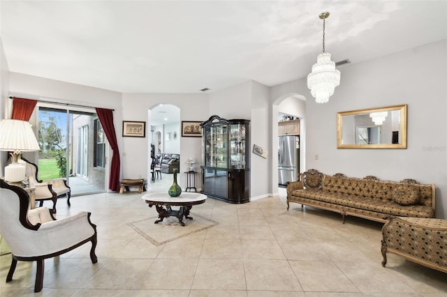 living area featuring light tile patterned floors, baseboards, arched walkways, and an inviting chandelier