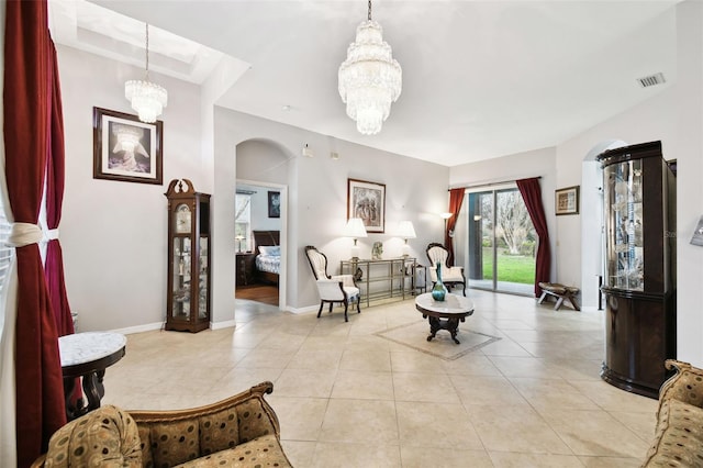 living room featuring arched walkways, a notable chandelier, light tile patterned floors, visible vents, and baseboards