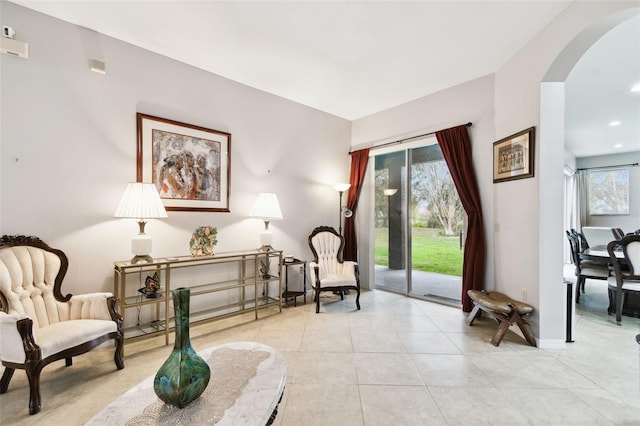 sitting room with arched walkways, light tile patterned floors, and baseboards