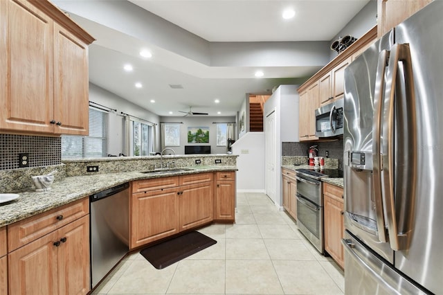 kitchen featuring light tile patterned floors, stainless steel appliances, a sink, light stone countertops, and tasteful backsplash