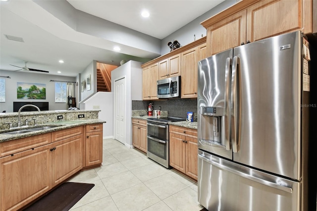 kitchen with light stone counters, light tile patterned flooring, a sink, appliances with stainless steel finishes, and tasteful backsplash