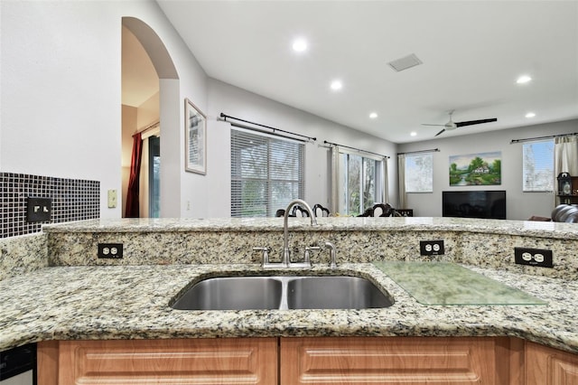 kitchen featuring light stone countertops, visible vents, open floor plan, and a sink