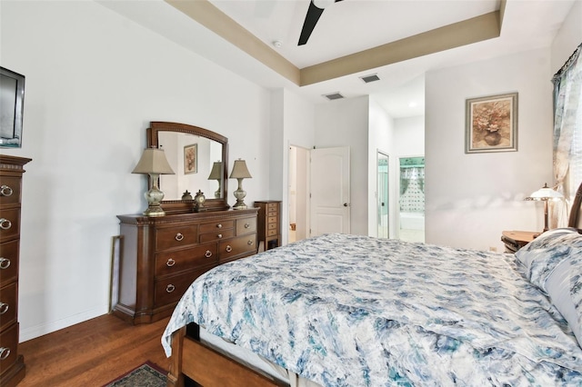 bedroom featuring a tray ceiling, dark wood finished floors, and visible vents