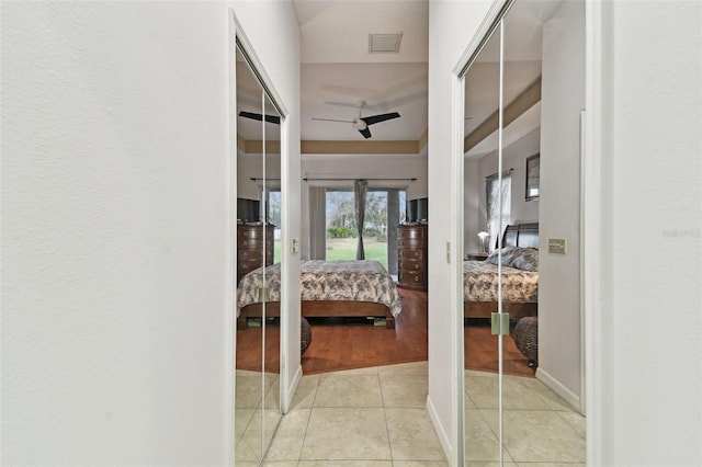 hall featuring visible vents, baseboards, and light tile patterned floors