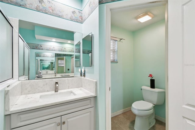 bathroom with toilet, a skylight, vanity, baseboards, and tile patterned floors