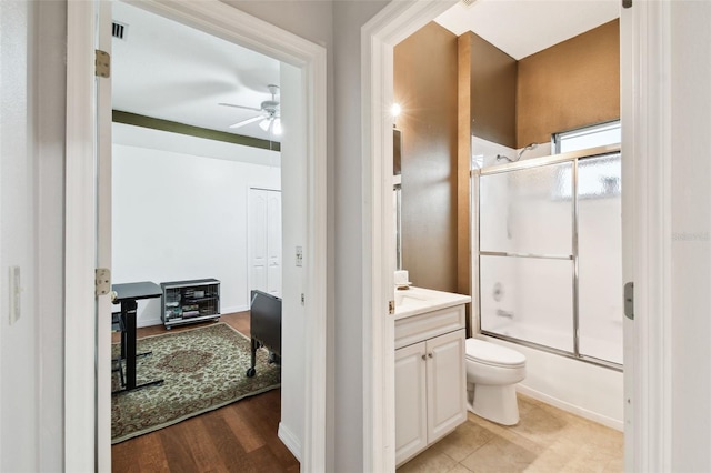 full bath with toilet, shower / bath combination with glass door, visible vents, vanity, and a ceiling fan