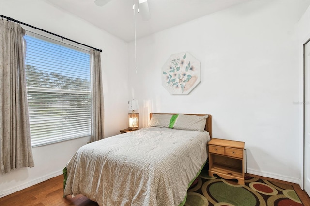 bedroom with ceiling fan, wood finished floors, and baseboards