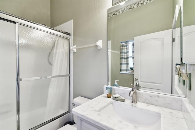 bathroom featuring toilet, combined bath / shower with glass door, and vanity