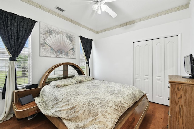 bedroom with dark wood-style floors, a ceiling fan, visible vents, and a closet