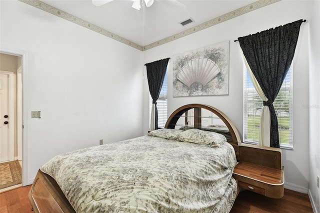 bedroom with dark wood-style flooring, visible vents, and multiple windows