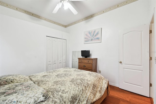 bedroom with dark wood-style floors, baseboards, a ceiling fan, and a closet