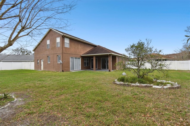 back of house featuring a fenced backyard, a lawn, and stucco siding