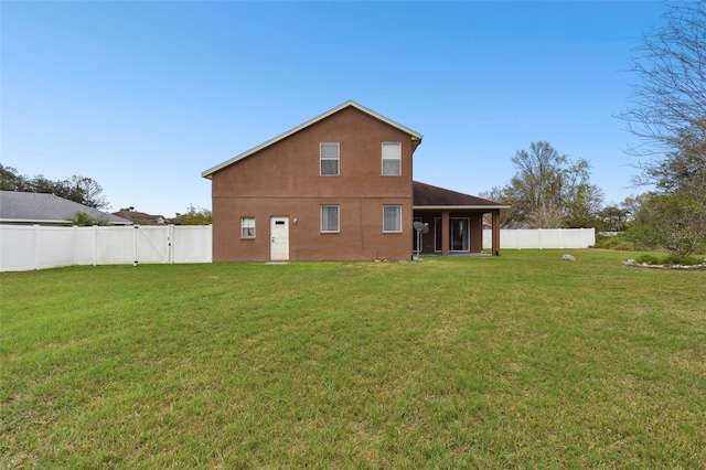 rear view of property with a yard, a fenced backyard, a gate, and stucco siding