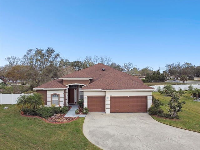 mediterranean / spanish home featuring stucco siding, concrete driveway, an attached garage, fence, and a front lawn