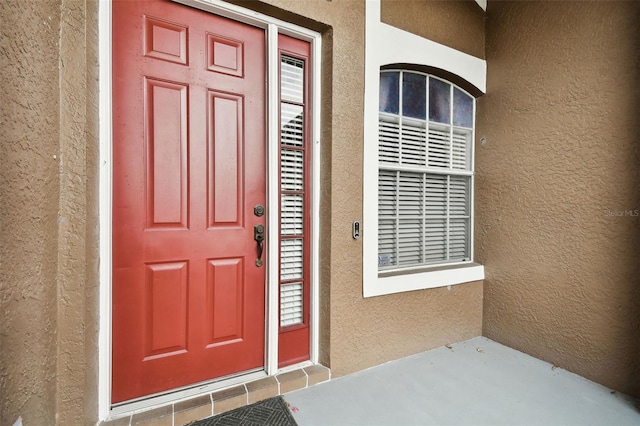 doorway to property featuring stucco siding