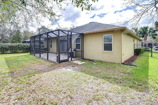 back of house featuring a lanai, fence, a lawn, and stucco siding