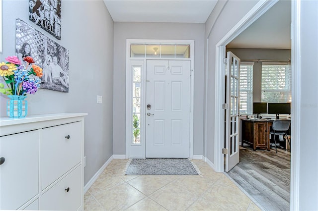 entryway with baseboards and light tile patterned floors