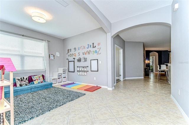 playroom featuring tile patterned flooring, visible vents, arched walkways, and baseboards