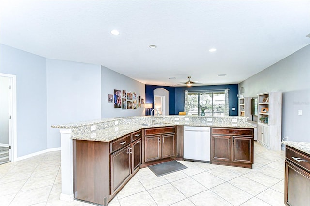 kitchen featuring arched walkways, light tile patterned flooring, a sink, light stone countertops, and dishwasher