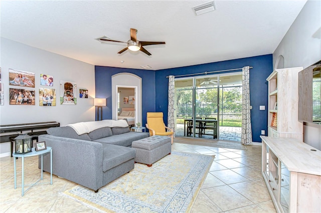 living room with light tile patterned floors, baseboards, visible vents, arched walkways, and a ceiling fan