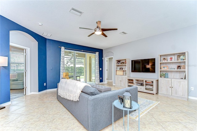 living room with light tile patterned floors, visible vents, and arched walkways