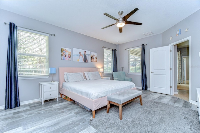 bedroom with light wood-type flooring, visible vents, ceiling fan, and baseboards