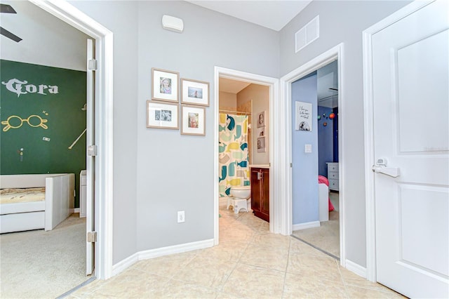 hallway featuring baseboards, visible vents, and tile patterned flooring