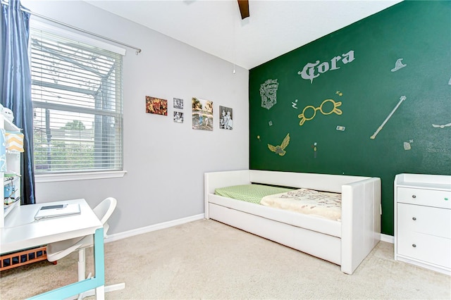 bedroom with an accent wall, light carpet, ceiling fan, and baseboards