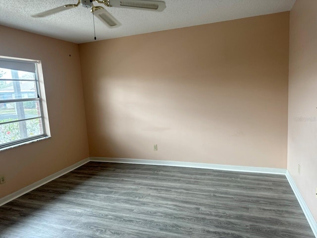 empty room featuring dark wood-style floors, ceiling fan, baseboards, and a textured ceiling