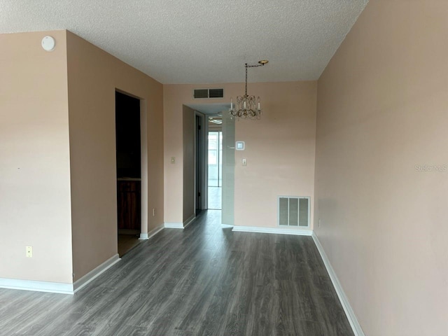 unfurnished dining area with an inviting chandelier, baseboards, visible vents, and dark wood-style flooring